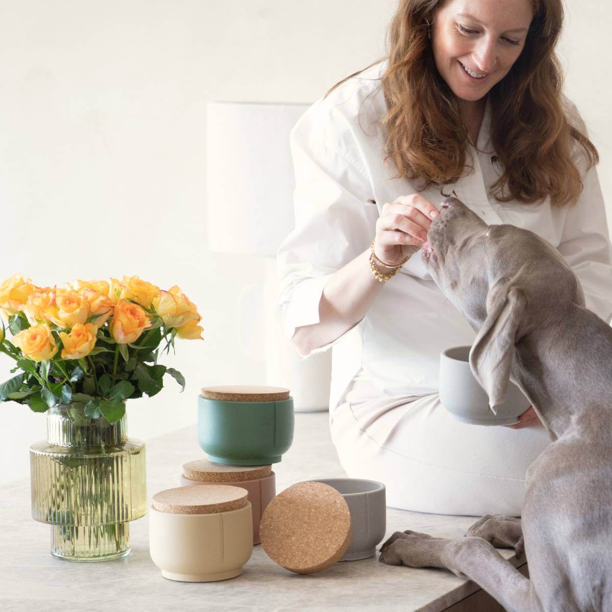 a person feeding a dog with the treat jar