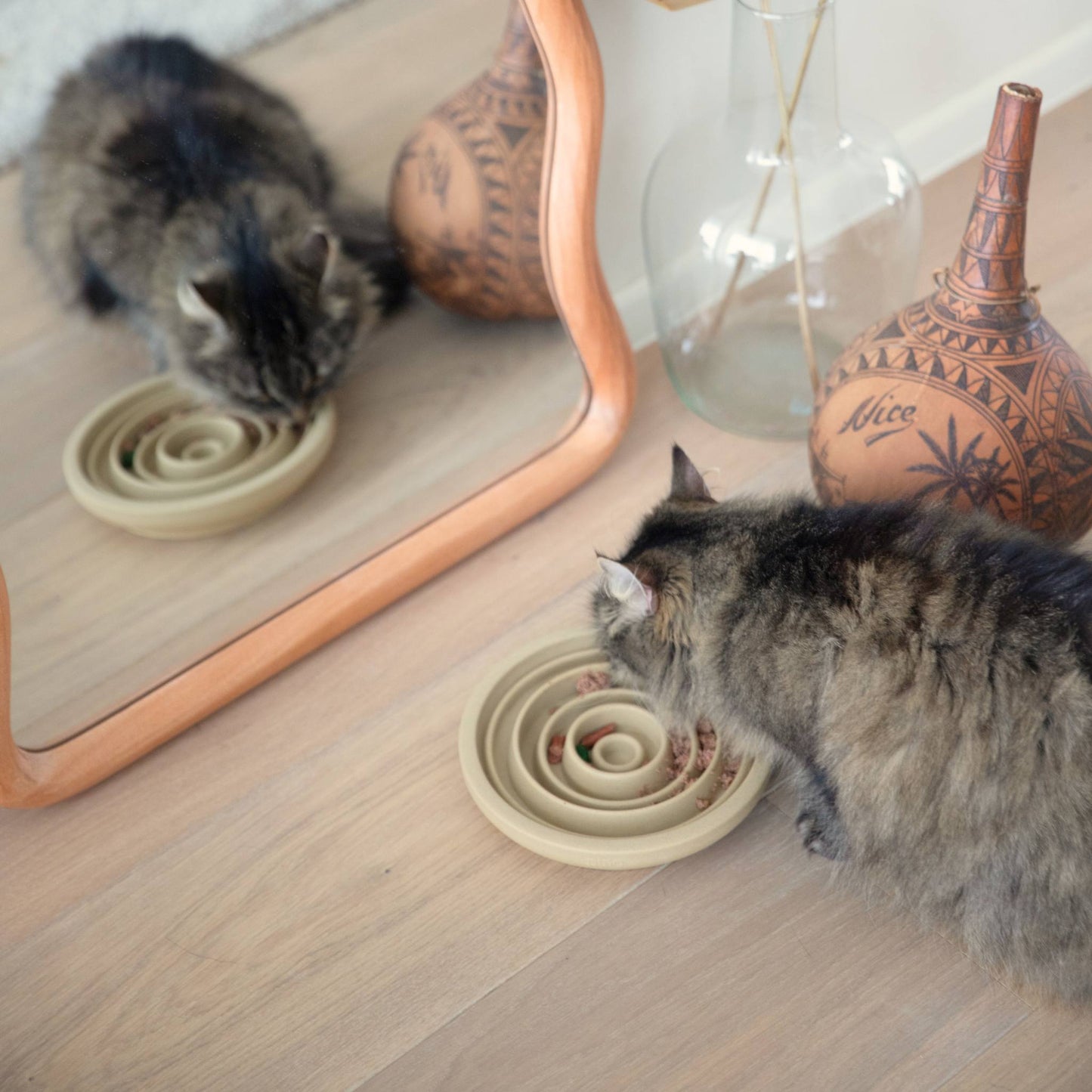 A cat eating out of the camel brown slow feeder